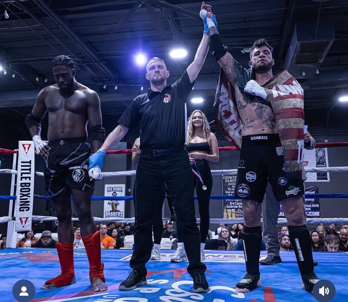 Boxing match referee raises winners arm in ring while opponent and spectators watch